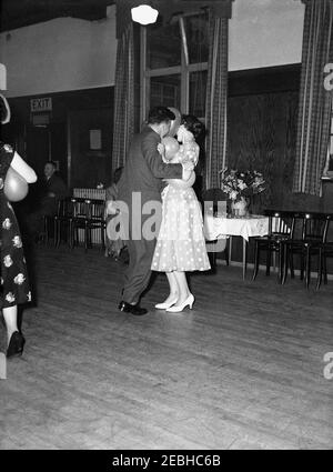 1950s, historical, a young couple doing a 'balllon' dance on a wooden dance floor at a birthday party in a function room at a hotel, England, UK. There are different versions of such a dance, but one is where the couple dance trying to hold the inflated ballon against their noses!. Stock Photo