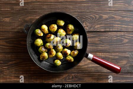 Roasted brussles sprouts in frying pan on wooden background with free text space. Top view, flat lay Stock Photo