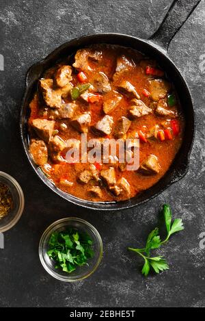 Stewed chicken livers in frying pan over black stone background. Top view, flat lay Stock Photo