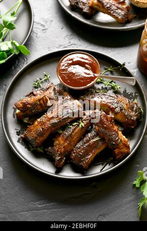 Grilled spare ribs on plate over black stone background. Stock Photo