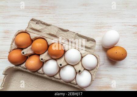 Carton container with brown and white chicken eggs on wooden table. Close-up brown and white eggs in recycled cardboard box on wood background. Free-r Stock Photo