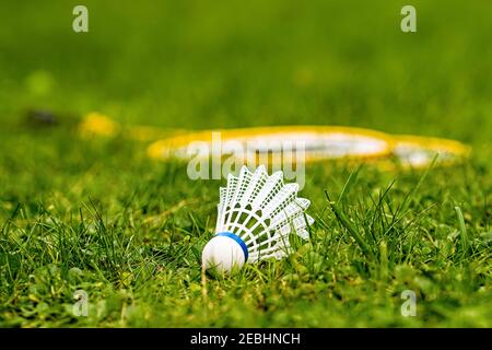 white shuttlecock close-up in a green meadow with yellow badminton rackets against a blurred background Stock Photo