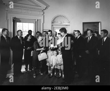 Presentation of the Thomas A. Dooley III Medal to Mrs. Agnes Dooley, 10:04AM. President John F. Kennedy presents the posthumous Dr. Thomas A. Dooley III Congressional Gold Medal to Dr. Dooleyu2019s mother, Agnes Wise Dooley (center left). Also pictured: Executive Director of Medical International Cooperation Organization (MEDICO), Malcolm W. Dooley, and Gabrielle Dooley and their children, Malcolm Jr., Thomas, and Michael; Representative Henry S. Reuss (Wisconsin); Senator John A. Carroll (Colorado); Director of the U.S. Mint, Eva Adams; Senator Claiborne Pell (Rhode Island); Representative F Stock Photo