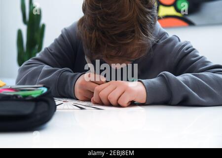 Teen drawing alone at home during covid-19 lockdown. Caucasian young boy doing homeworks. Student learning in pandemic days Child study at home school Stock Photo
