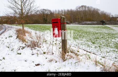 Red British post box, winter time. Pole mounted English mailbox in the countryside. Winter, snowy day Stock Photo