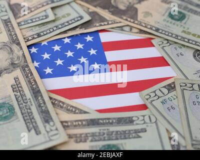 The stars and stripes of a United States of America USA flag are shown surrounded by twenty dollar bills up close. Stock Photo