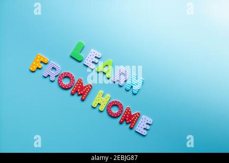 Words LEARN FROM HOME written of colorful wooden letters on blue background. Inscription learn from home on board with copy space. Homeschooling. Home Stock Photo
