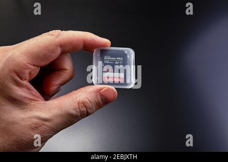 St. Petersburg, Russia - January 9, 2021: Close-up hand holds SanDisk extreme PRO 64GB SDXC memory card up to 170MB / s, class 10, U3, V30. Stock Photo