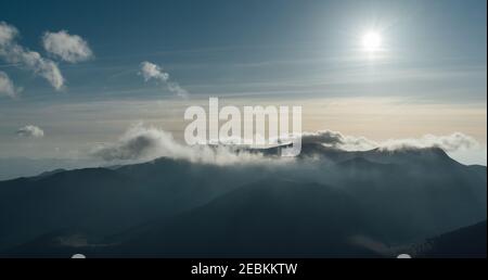 Slovakian Tatry mountain landscape view from Velky Rozsutec mountain. Sun is going down in the evening and lights up clouds over the peaks. Stock Photo