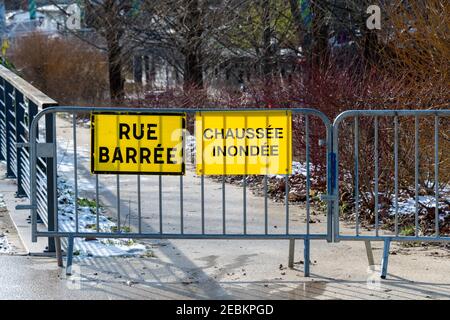 Weather - Flood warnings in France. Two yellow warning signs fixed on a metal fence and written in French: 'Closed street' and 'Flooded pavement' Stock Photo