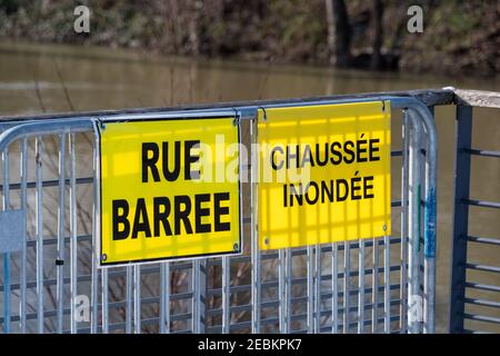 Weather - Flood warnings in France. Two yellow warning signs fixed on a metal fence and written in French: 'Closed street' and 'Flooded pavement' Stock Photo