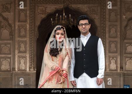 Bride wearing traditional wedding dress posing with groom at Badshahi Mosque, Lahore, Punjab, Pakistan Stock Photo