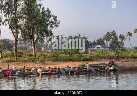 Patel Nagar, Karnataka, India - November 9, 2013: Tungabhadra Canal. Women in coloful saris and shirts stand feed in water doing family laundry. Green Stock Photo