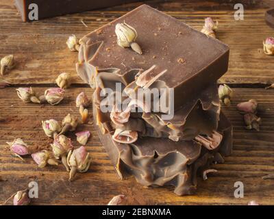 Bars of homemade chocolate soap and roses, on an old wooden background Stock Photo