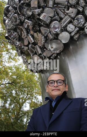 The artist Subodh Gupta poses for photos in front of his new installation called Soak Becomes Spill, which stands six metres high overflowing with pot Stock Photo