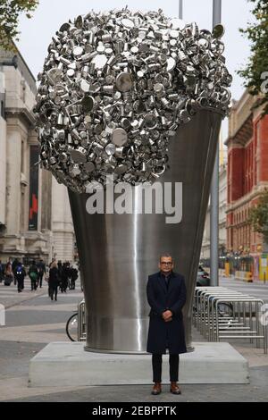 The artist Subodh Gupta poses for photos in front of his new installation called Soak Becomes Spill, which stands six metres high overflowing with pot Stock Photo