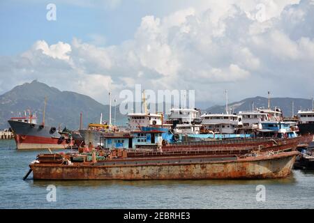 Fishing boats both large and small lined up in a bay near seaworld in Shenzhen, China. Rusted metal and wooden ships. Stock Photo