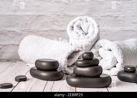 Spa stones for massage by white towels on wooden table copy space Stock Photo