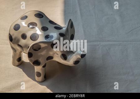 Elephants shaped ceramic on white textured table cloth. Home decor, Copy space, No focus, specifically. Stock Photo