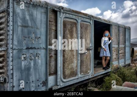 Girl in a train scrap yard posing for a photograph inside a disused rusting vintage railway goods carriage. Thailand, Southeast Asia. Freight wagon Stock Photo