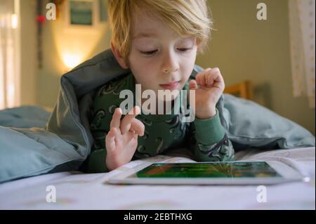 Boy (6-7) on bed using digital tablet Stock Photo