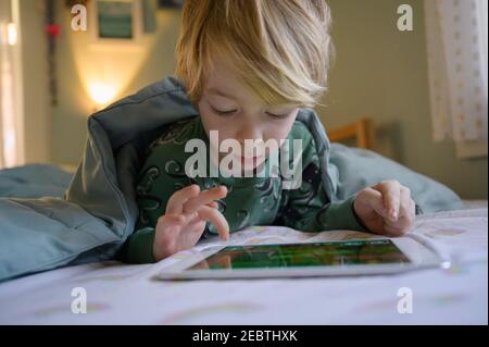 Boy (6-7) on bed using digital tablet Stock Photo