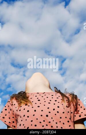 Low angle view of girl (8-9) under cloudy sky Stock Photo