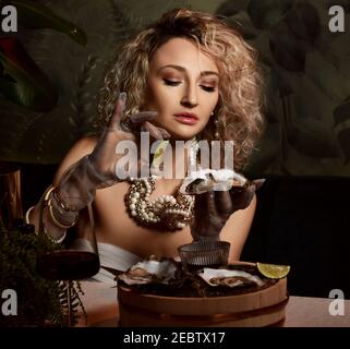 Portrait of beautiful blonde curly hair woman gourmet in seafood restaurant eating oysters squeezing lime juice onto one Stock Photo