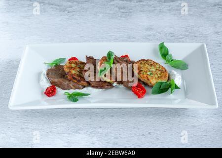 Fried grilled slices of beef fillet with vegetable zucchini and cabbage pancakes Stock Photo