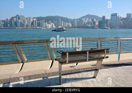 Bench overlooking the Hong Kong skyline in the popular tourist area avenue of stars. Star ferry in the distance. Stock Photo