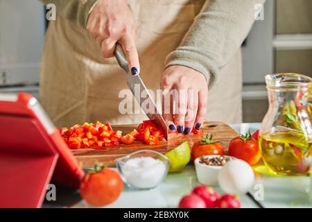 Woman cooking according the tutorial of online virtual master class, And looking on the digital recipe, using touchscreen tablet while cooking healthy Stock Photo