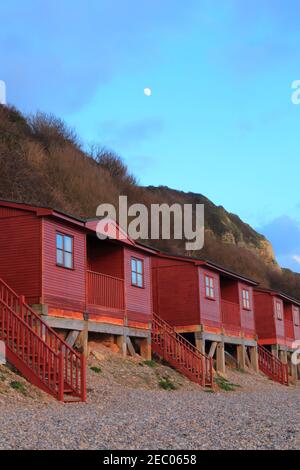 Red beach huts in village of Branscombe, Devon on the Jurassic Coast Stock Photo