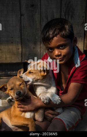 A boy is playing with a dog on the street site.Khulna,Bangladesh.February 7,2020. Stock Photo