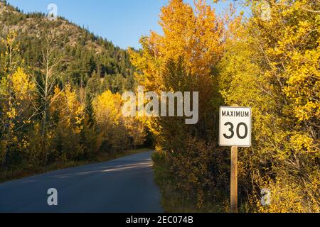 Maximum 30 km speed limit sign in Vermilion Lakes road in autumn foliage season sunny day. Banff Legacy Trail, Banff National Park, Canadian Rockies, Stock Photo