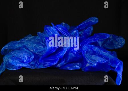 discarded and new blue virus inspection plastic gloves isolated on a black background Stock Photo