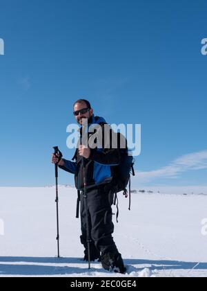 Vertical shot of a male happily standing on the snowy ground Stock Photo