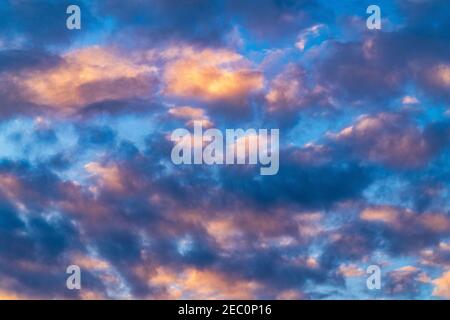 Beautiful clouds in blue sky, illuminated by rays of sun at colorful sunset to change weather. Soft focus, motion blur summer cloudscape background. Stock Photo