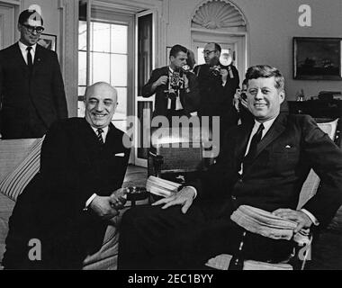 Meeting with the Prime Minister of Italy Amintore Fanfani, 11:40AM. President John F. Kennedy (in rocking chair) meets with Prime Minister Amintore Fanfani of Italy in the Oval Office of the White House, Washington, D.C. State Department Interpreter, Neil Seidenman, stands at left; photographers are unidentified. Stock Photo