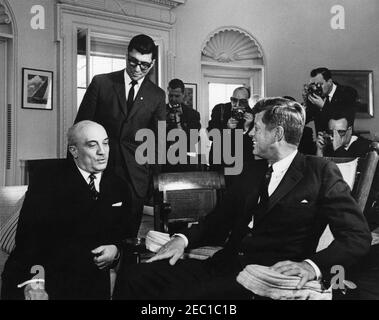 Meeting with the Prime Minister of Italy Amintore Fanfani, 11:40AM. President John F. Kennedy (in rocking chair) meets with Prime Minister Amintore Fanfani of Italy in the Oval Office of the White House, Washington, D.C. State Department Interpreter, Neil Seidenman, stands at left; photographers are unidentified. Stock Photo