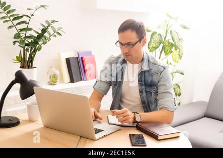Focused young businessman holding video call with clients on laptop. Concentrated millennial man in glasses giving online educational class lecture Stock Photo