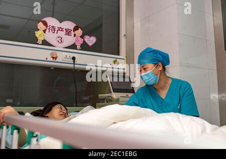 (210213) -- URUMQI, Feb. 13, 2021 (Xinhua) -- A midwife talks with an expectant mother at the maternity ward of Urumqi Maternal and Child Health Hospital in Urumqi, northwest China's Xinjiang Uygur Autonomous Region, Feb. 11, 2021. With advanced equipment and sufficient personnel, Urumqi Maternal and Child Health Hospital has one of the most popular maternity wards in the region.Medical workers here stick to their posts during the Spring Festival vacation. To better control and prevent the COVID-19 pandemic, negative nucleic acid testing reports are required for all expectant mothers before th Stock Photo