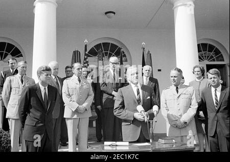 Swearing-in ceremony, Gen. Maxwell Taylor, Chairman, JCS, 12:00PM. Deputy Secretary of Defense, Roswell Gilpatric (center right, at microphones), delivers remarks during the swearing-in ceremony of General Maxwell D. Taylor as Chairman of the Joint Chiefs of Staff (JCS). President John F. Kennedy observes from left; General Taylor and Attorney General, Robert F. Kennedy, stand at right. Looking on from the steps of the West Wing Colonnade, beginning at the very back (left to right): Naval Aide to the President, Captain Tazewell T. Shepard, Jr.; Military Aide to the President, General Chester V Stock Photo