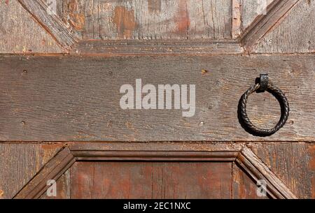 Detail of an old wooden exterior church door with a large round iron knocker Stock Photo