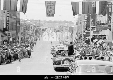 Trip to Western States: Pueblo, Colorado, 12:50PM. President John F. Kennedy stands in a convertible as his motorcade travels down 4th Street in Pueblo, Colorado. Crowds line the street. Stock Photo