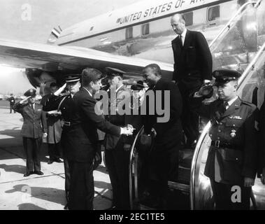 Arrival ceremony for Sylvanus Olympio, President of Togo, 11:00AM. President John F. Kennedy (left) shakes hands with President of Togo, Sylvanus Olympio, upon President Olympiou2019s arrival in Washington, D.C. US Chief of Protocol, Angier Biddle Duke, walks down airplane stairs behind President Olympio. White House Secret Service agent, Roy Kellerman, stands at left in background. All others are unidentified. Military Air Transport Service (MATS) Terminal, Washington National Airport, Washington, D.C. Stock Photo