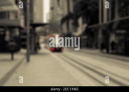 Sombre and gloomy city street perspective with a bright red tram coming to the camera. City blurry background Stock Photo