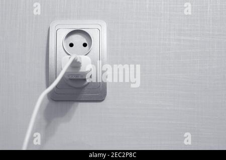 the cord is plugged into an outlet, to charge the phone, a place for text Stock Photo