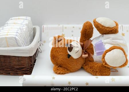 Pcture of a brown teddy bear with diaper on sitting in baby bed Stock Photo