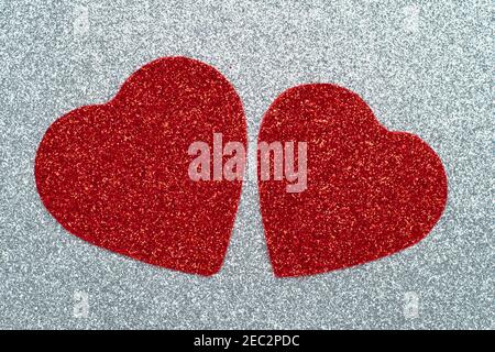 Two carved red hearts on a gray glossy background. Abstract shiny pattern. Craft paper, glitter, sparkling texture. Love concept Stock Photo