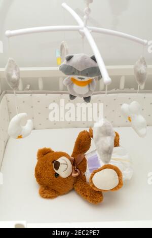 Pcture of a brown teddy bear with diaper on sitting in baby bed Stock Photo